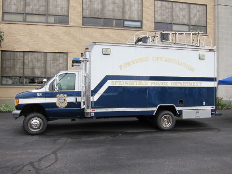 1991 Ford LTD Crown Victoria - Front three-quarter view of a blue-and-white Springfield Police Forensic Investigation box truck, unit 88, parked by a building.