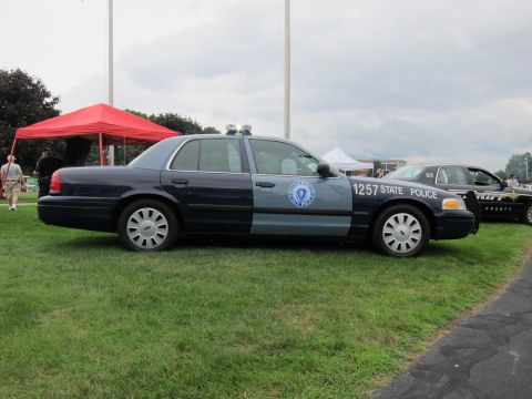 1991 Ford LTD Crown Victoria - Profile view of a two-tone blue Ford Crown Victoria marked 1257 State Police parked on grass near tents and another cruiser.