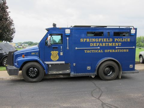 1991 Ford LTD Crown Victoria - blue Springfield Police Department 'Tactical Operations' armored box truck parked at the curb with a department badge on the cab.