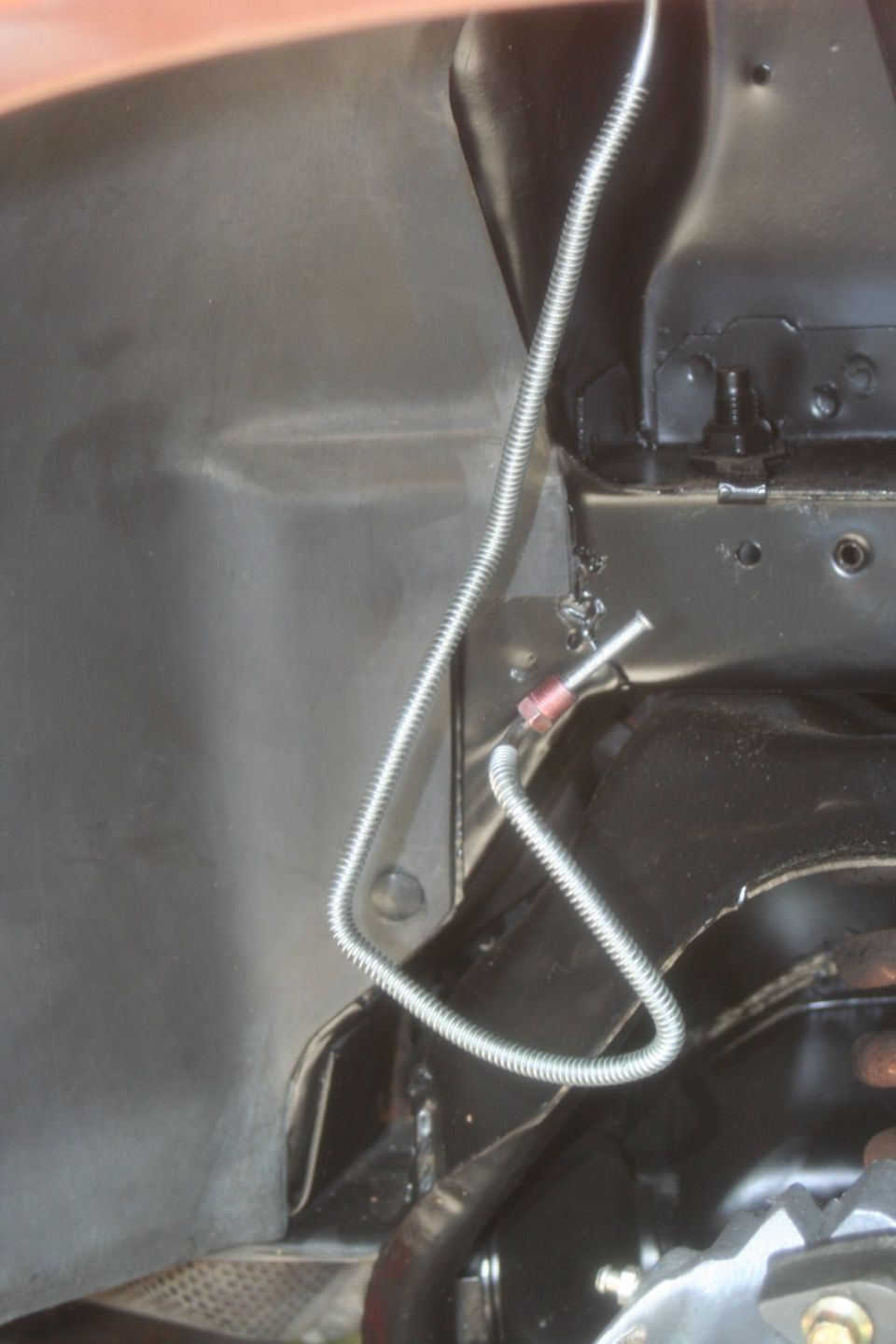 Close-up of a metal brake line running along the underside of a vehicle, near suspension parts