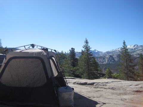1989 Ford Bronco - Camping scene with a tent pitched on a rock ledge overlooking a mountainous landscape.