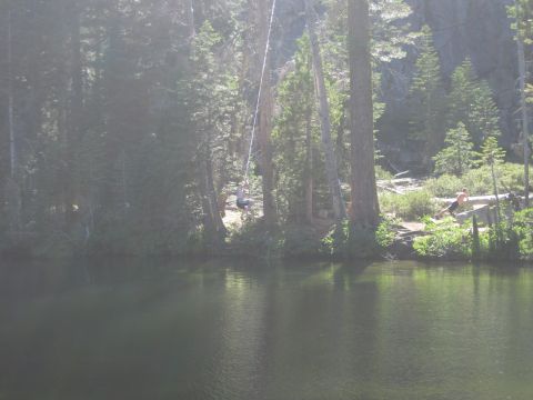 1989 Ford Bronco - People enjoy a sunny day by a lake, with one person on a rope swing and another near the water's edge.