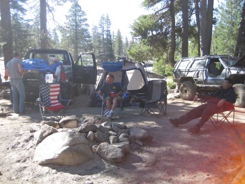 1989 Ford Bronco - A campsite scene with two off-road vehicles, a tent, and people enjoying the outdoors.