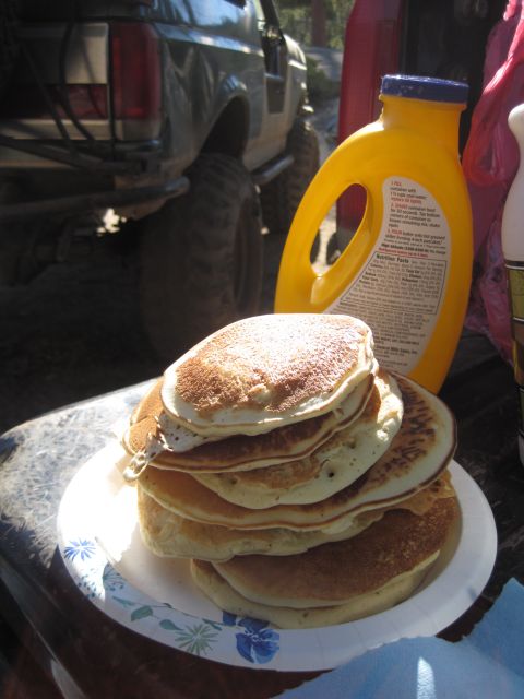 1989 Ford Bronco - A stack of pancakes sits on a paper plate next to a yellow bottle of pancake mix, with a modified Ford Bronco in the background.
