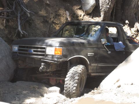 1989 Ford Bronco - This Ford Bronco is navigating a difficult off-road trail, wedged between large rocks.