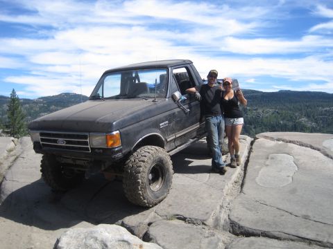 1989 Ford Bronco - A black Ford F-Series truck is parked on a rocky overlook with two people standing beside it.