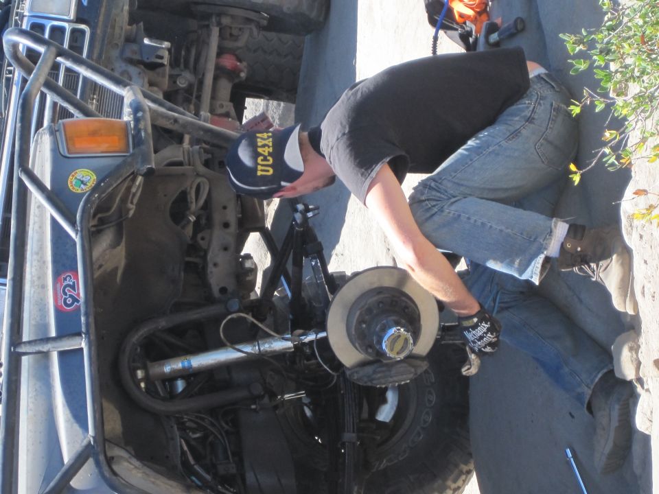 Person working on brake assembly of an off-road vehicle. A blue shock absorber is visible
