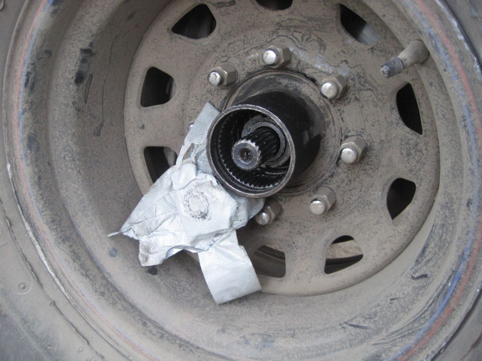 Close-up of a wheel hub with splines, covered partially with duct tape. Lug nuts are visible