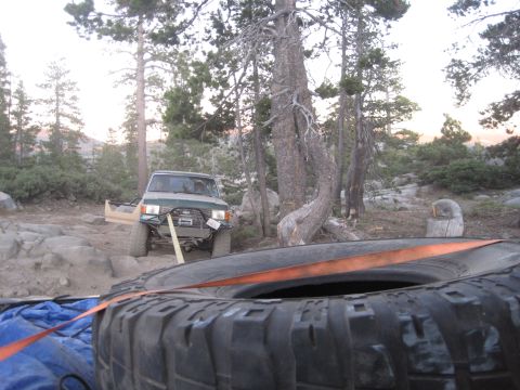 1989 Ford Bronco - A green 1989 Ford Bronco is winched forward on a rocky trail, with a spare tire in the foreground.