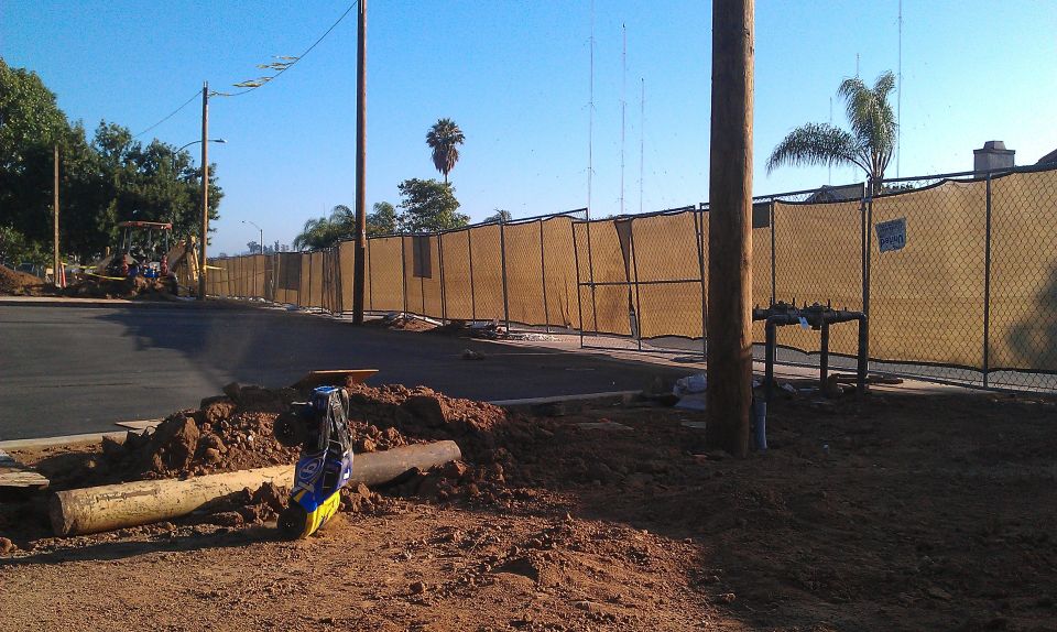 Construction scene with yellow backhoe and chain-link fence