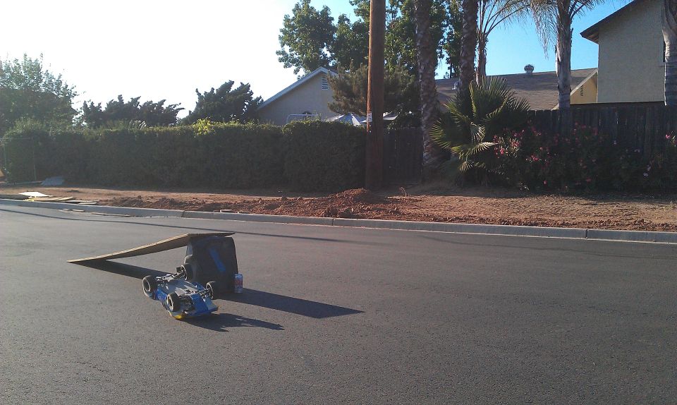Blue remote control car on asphalt with a ramp and bag