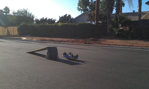 1992 Ford Ranger - A blue remote control car lies on its side on an asphalt street, with a makeshift ramp nearby.