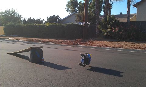 1992 Ford Ranger - A remote control car is on its side on the street near a makeshift ramp.