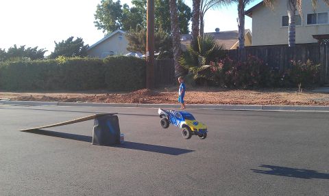 1992 Ford Ranger - RC monster truck mid-air jump with a homemade ramp set up on a suburban street.
