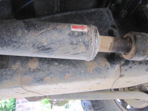2008 Jeep Wrangler - Underside view of a dirty driveshaft with a red arrow sticker indicating direction.