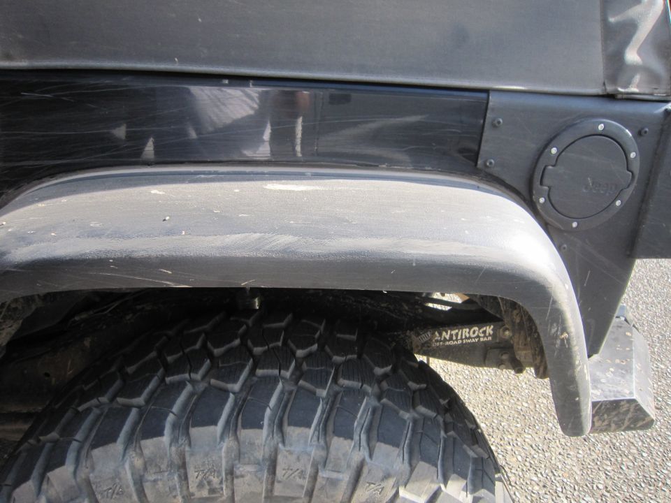 Jeep Wrangler rear fender, fuel door, and off-road tire. 'ANTTROCK OFF-ROAD SWAY BAR' is visible