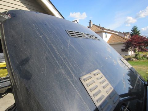 2008 Jeep Wrangler - The dusty hood of a black vehicle is shown from a close-up angle, revealing two vents and numerous scratches.