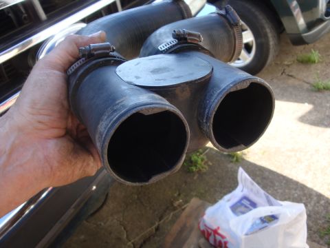 1989 Ford Bronco - A hand holds a black air intake hose with two outlets, with a vehicle visible in the background.