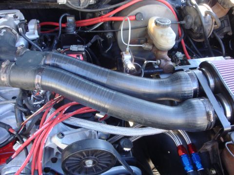 1989 Ford Bronco - Close-up view of an engine bay, highlighting dual intake pipes and red spark plug wires.