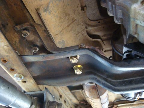 1989 Ford Bronco - Close-up view of the undercarriage of a vehicle, showing frame components, bolts, and exhaust system.