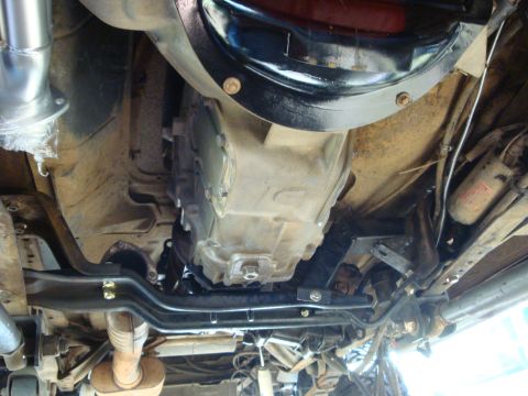 1989 Ford Bronco - The underside of a vehicle shows the transmission, exhaust pipes, and suspension components.