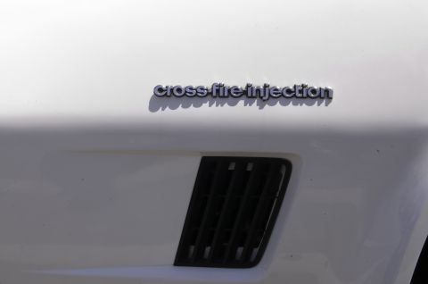 2006 Cadillac STS - Detail of a white car fender a "cross-fire injection" badge and a black vent.