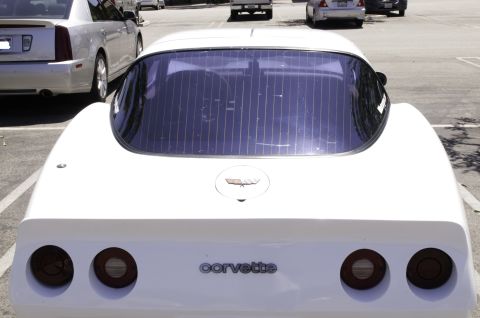 2006 Cadillac STS - The rear of a white Corvette is shown, with a Cadillac parked alongside it in a parking lot.