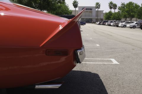 2006 Cadillac STS - A close-up of a red car's rear fin and bumper is visible in a parking lot.