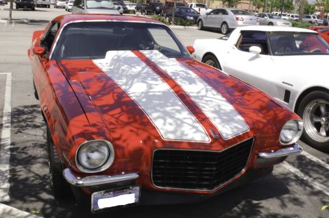 2006 Cadillac STS - Front view of a red muscle car with white racing stripes, parked in a lot next to another vehicle.