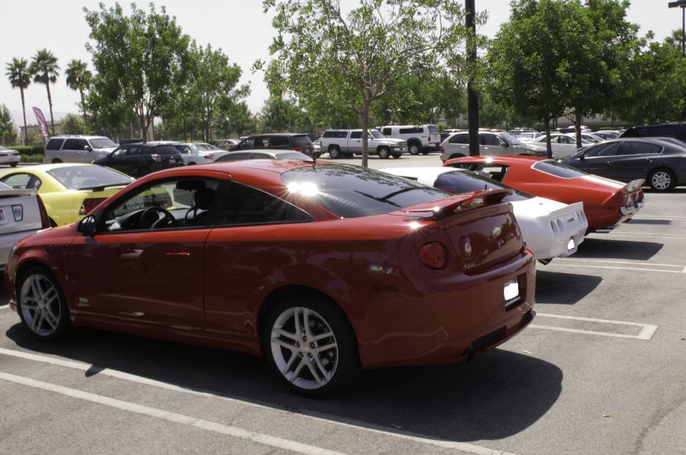 Red coupe rear view, parked in a lot with other cars
