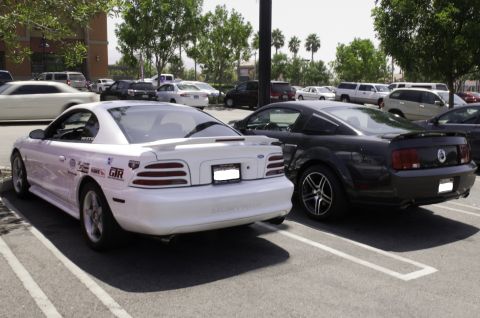 2006 Cadillac STS - Two Ford Mustangs, one older generation and one newer, are parked side-by-side in a lot.