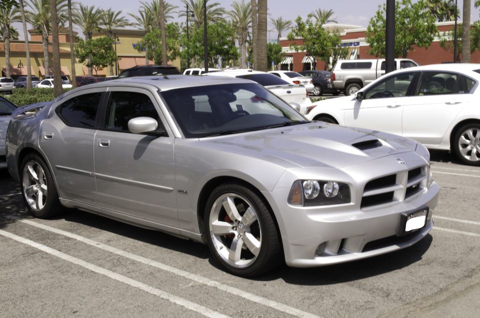 Silver Dodge Charger SRT8 sedan with hood scoop parked in a palm-lined parking lot