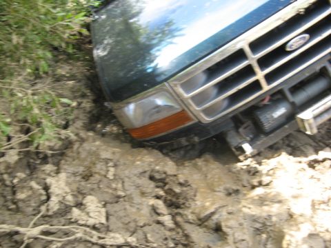 1995 Ford Bronco - This 1995 Ford Bronco appears to be stuck deep in mud, with its front grille and winch partially submerged.