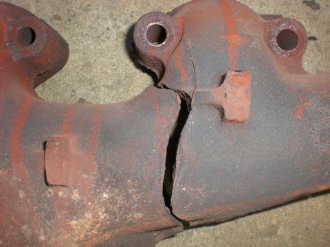 1972 Cadillac Fleetwood - Exhaust manifold shows a large crack down the center, indicating damage.