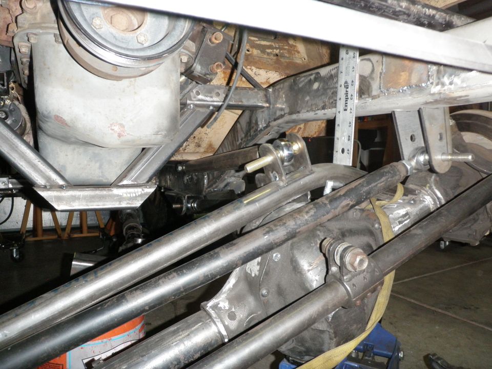 Close-up of a vehicle's rear axle, differential, and suspension linkage, with a ruler measuring clearance