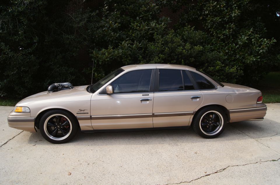 Side view of a tan 1993 Ford Crown Victoria with a large hood scoop and black rims