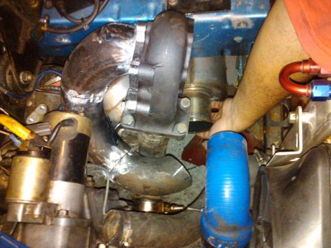 1995 Ford Probe - Custom turbocharger piping is installed with a blue silicone hose and a hand guiding the connection.