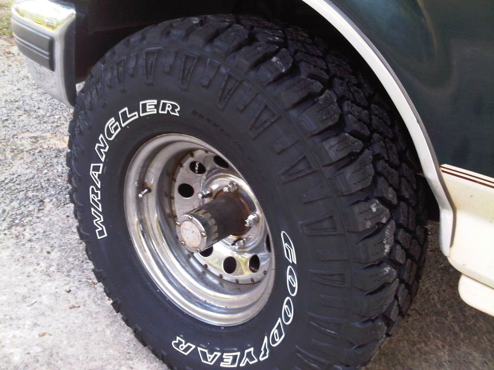 Goodyear Wrangler tires on a dark green and beige vehicle