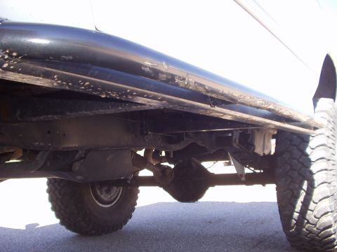 1993 Ford Bronco - The underside of a truck is visible, with focus on the frame rails and suspension components.