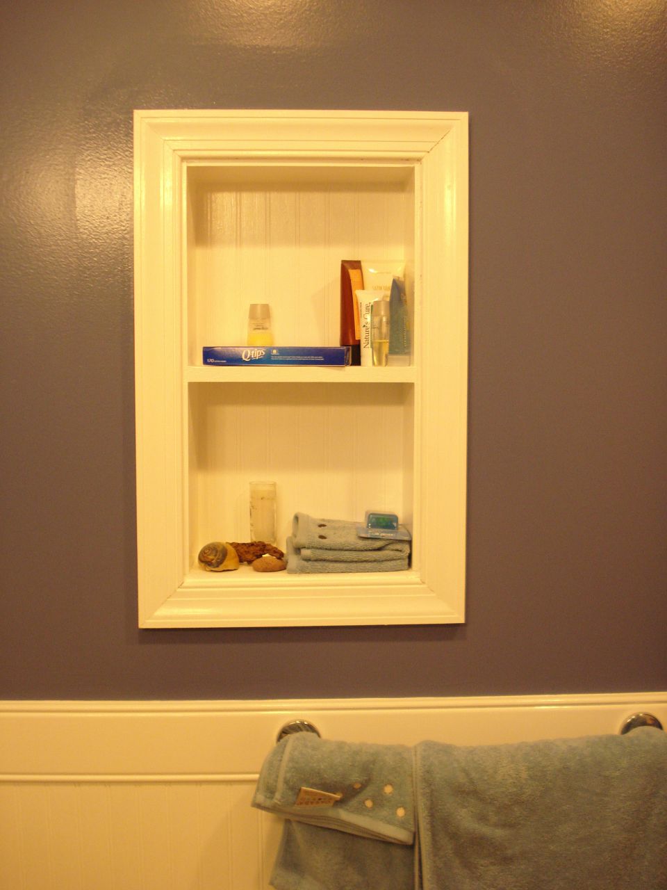Built-in white bathroom wall shelf with toiletries and towels; no vehicle shown
