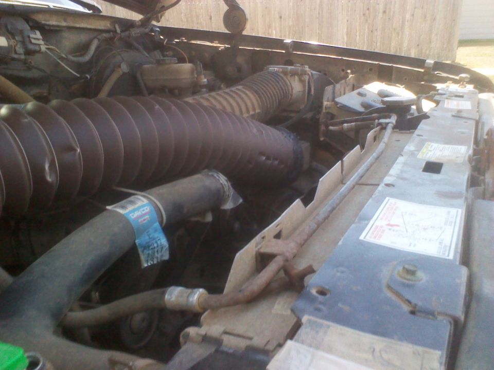 Engine bay with large air intake hose and radiator. Visible text on hose and radiator