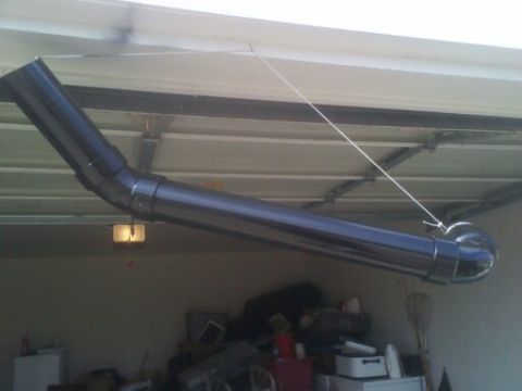 1995 Ford Bronco - A black exhaust pipe is suspended from the ceiling of a garage.