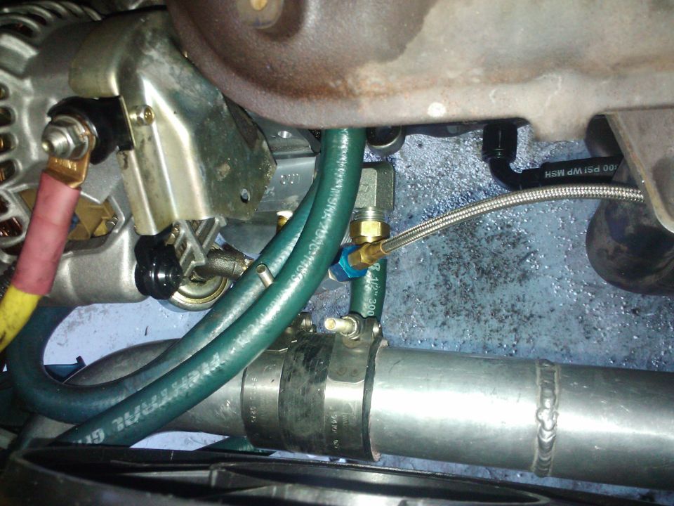 Engine hoses and metal pipes with a braided line connected to a blue fitting