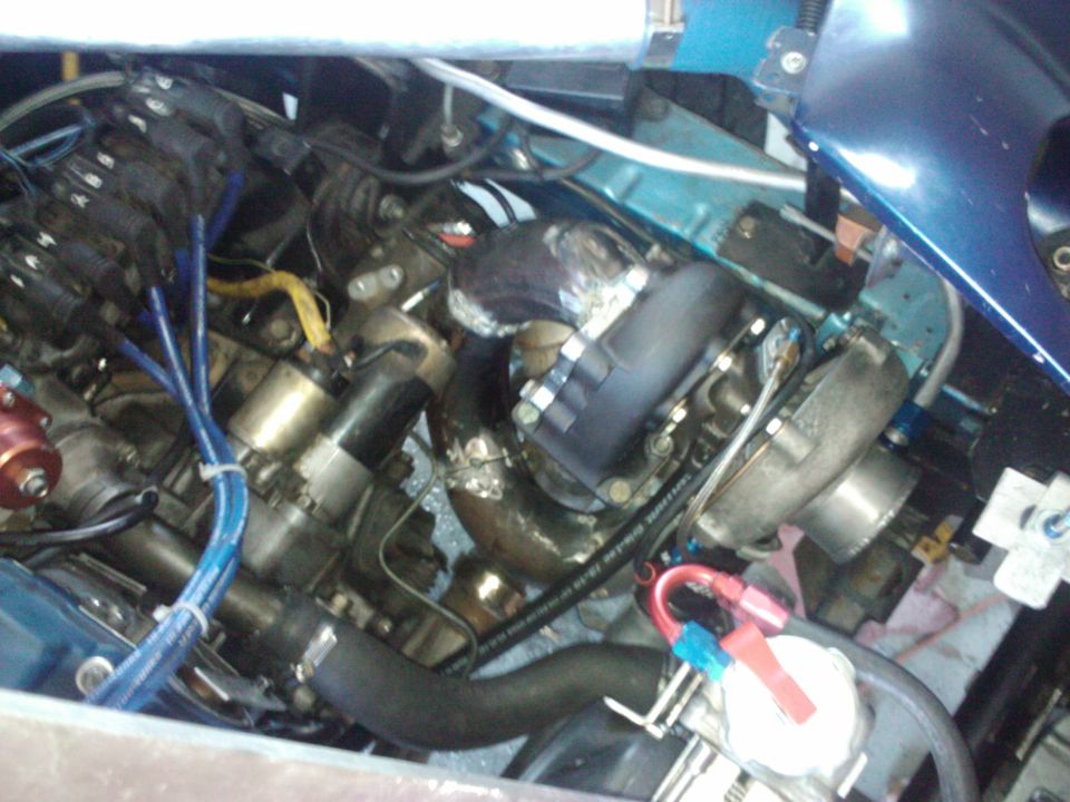 Engine bay with turbocharger, exhaust manifold, and various hoses and wires