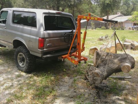 1995 Ford Bronco - A silver Ford Bronco is shown with an engine hoist preparing to lift a large log.