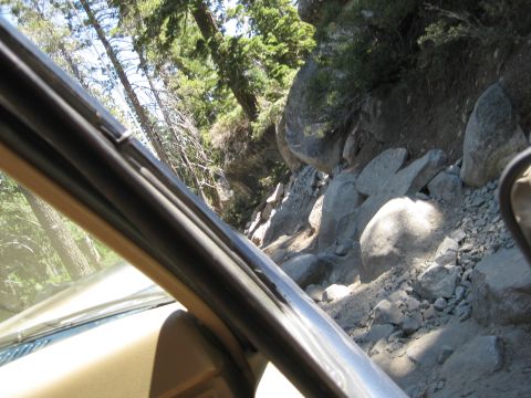 1986 Ford Bronco - The view from inside a vehicle navigating a challenging, rocky off-road path.