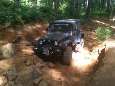 2005 Jeep Wrangler - A Jeep Wrangler is shown on a challenging off-road trail with steep inclines and rocky terrain.