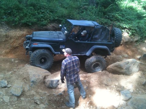 2005 Jeep Wrangler - A black Jeep Wrangler navigates a challenging rocky trail with a person standing nearby.
