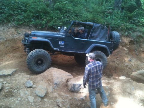 2005 Jeep Wrangler - A Jeep Wrangler tackles a challenging off-road course, with a spotter guiding the driver through the terrain.