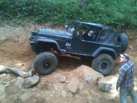 2005 Jeep Wrangler - A Jeep navigates a rocky off-road course with a person watching.